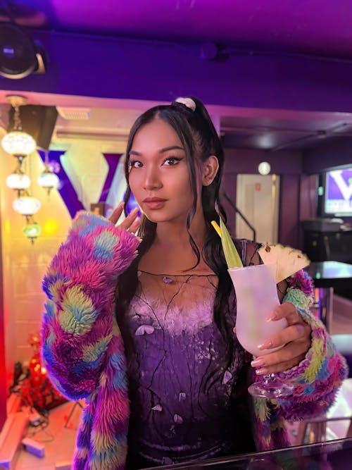 A Woman Wearing a Colorful Jacket while Holding a Drink