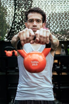 A focused athlete lifting a kettlebell during a gym workout session, showcasing strength and discipline.