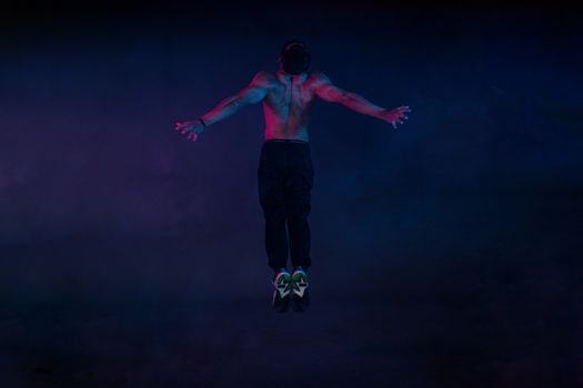 Energetic dancer caught mid-jump in dramatic lighting, showcasing athleticism and movement.