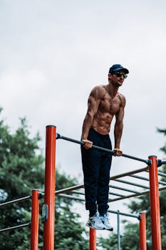 Athletic man showcasing strength in outdoor gym with trees in background.