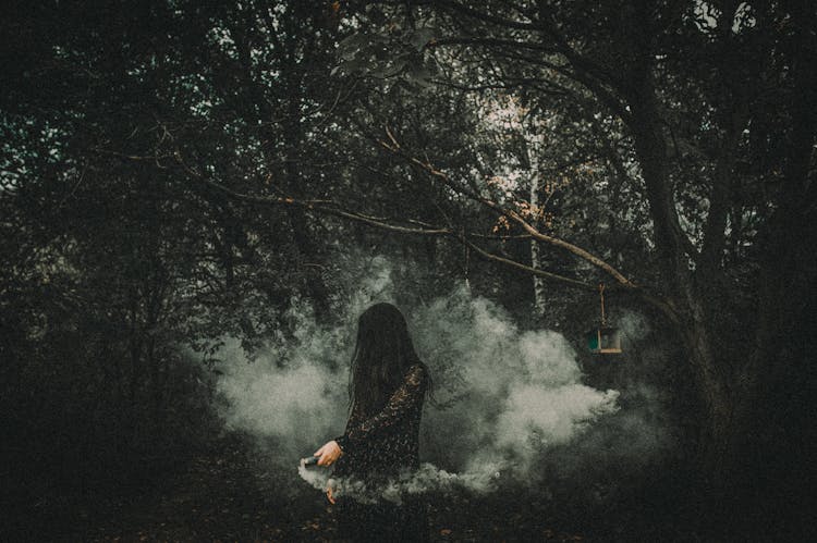 A Woman I Black Dress Holding A Smoke Bomb