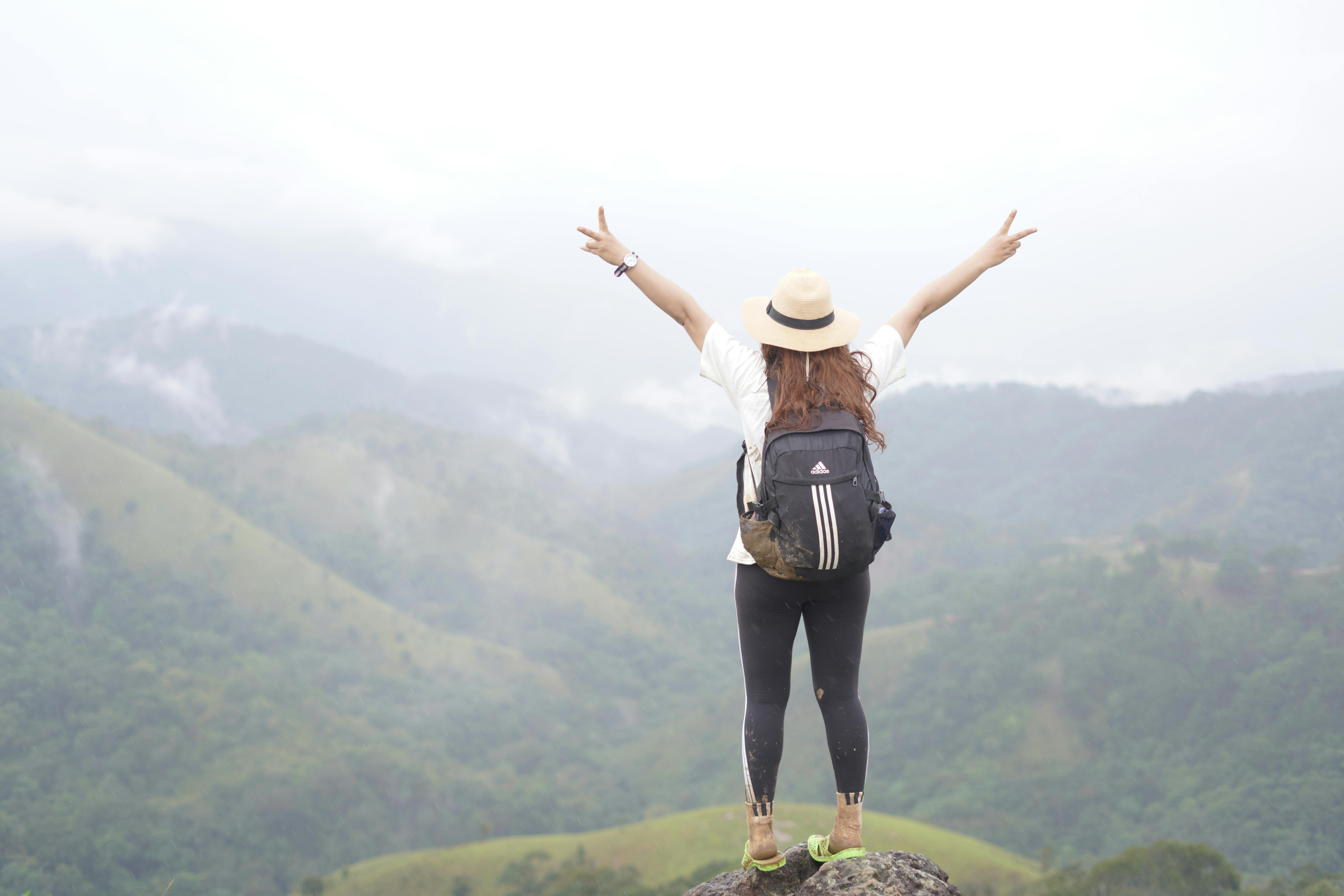 A woman hiker on a mountain top celebrating the scenic view with open arms.