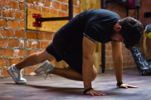 Man working out indoors, performing push-up exercise against a brick wall.