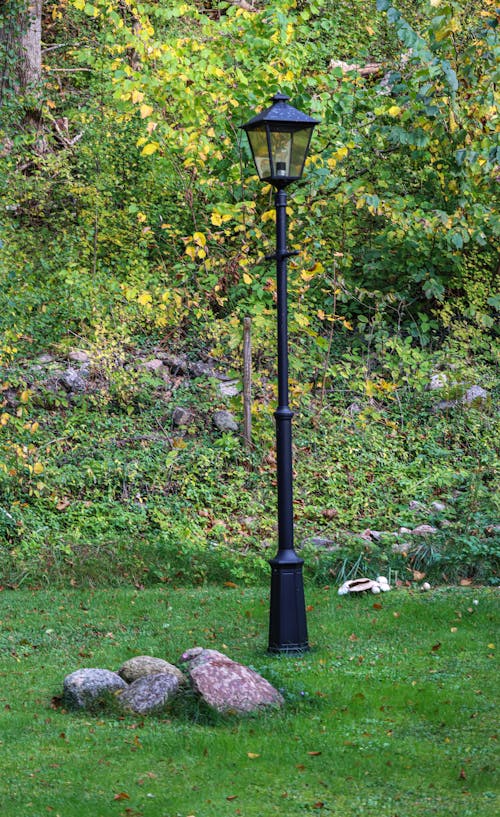 Black Streetlamp on Green Grass Field Near Rocks