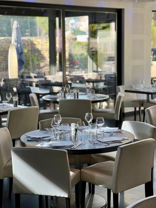 Free Stylish restaurant interior featuring round tables and modern decor with natural light. Stock Photo