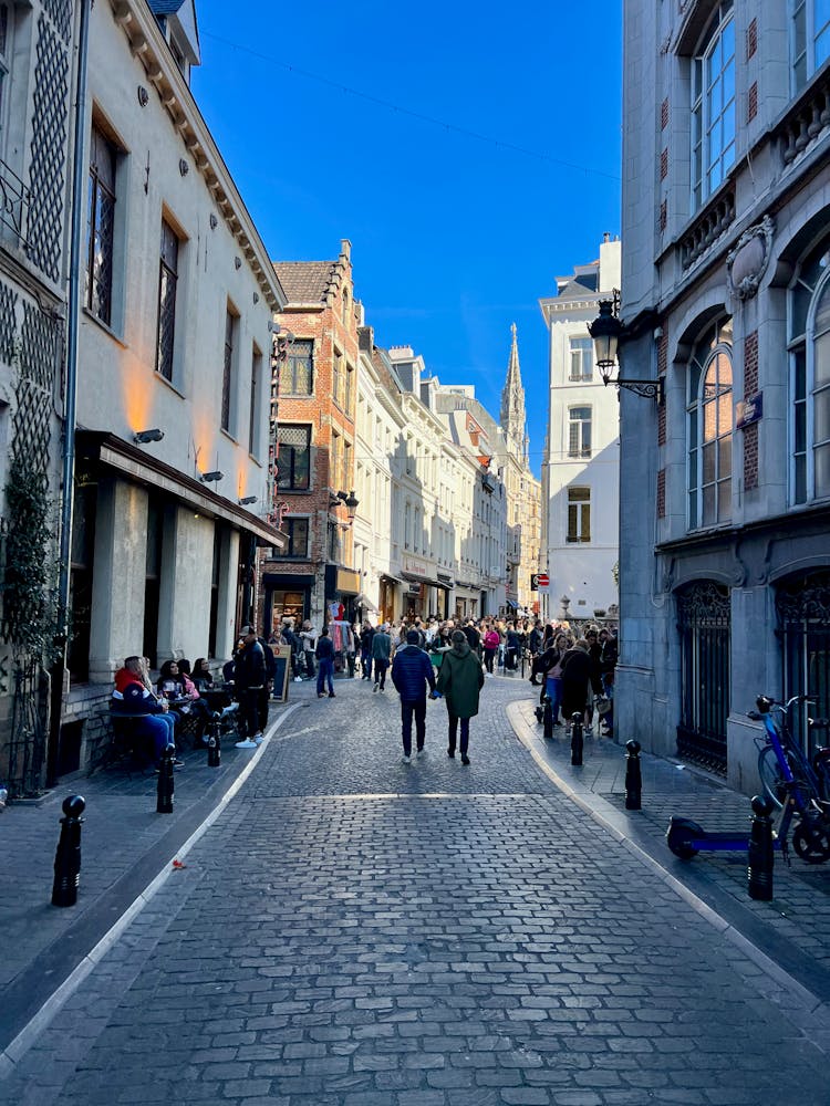 People Walking On The Street Between Buildings