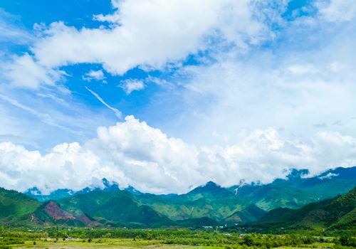 Free Beautiful scenic view of lush green mountain range under a vibrant blue sky with clouds. Stock Photo