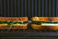 Close-up of spinach and cheese sandwiches grilling, showcasing fresh ingredients and artisanal bread.
