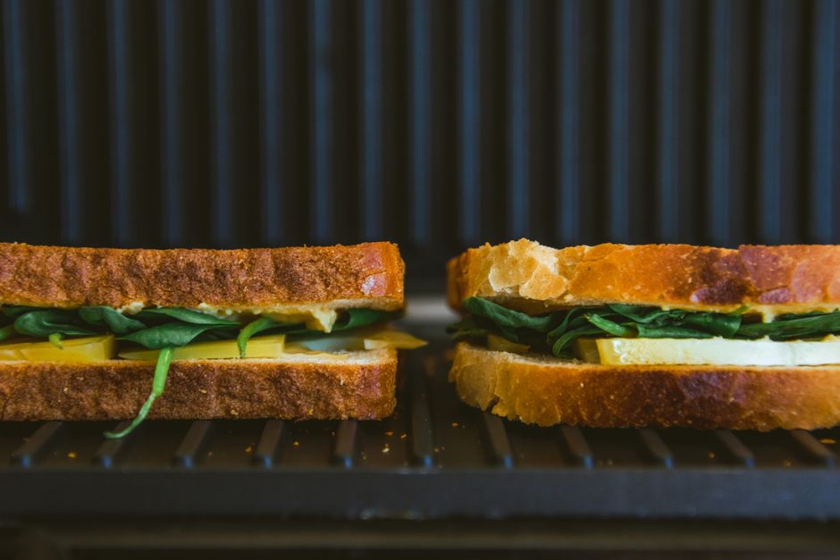 Close-up of spinach and cheese sandwiches grilling, showcasing fresh ingredients and artisanal bread.