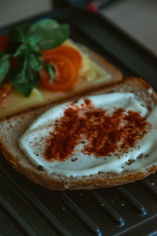 Free Fresh open-faced sandwich with cream cheese, paprika, tomatoes, and basil on bread. Stock Photo