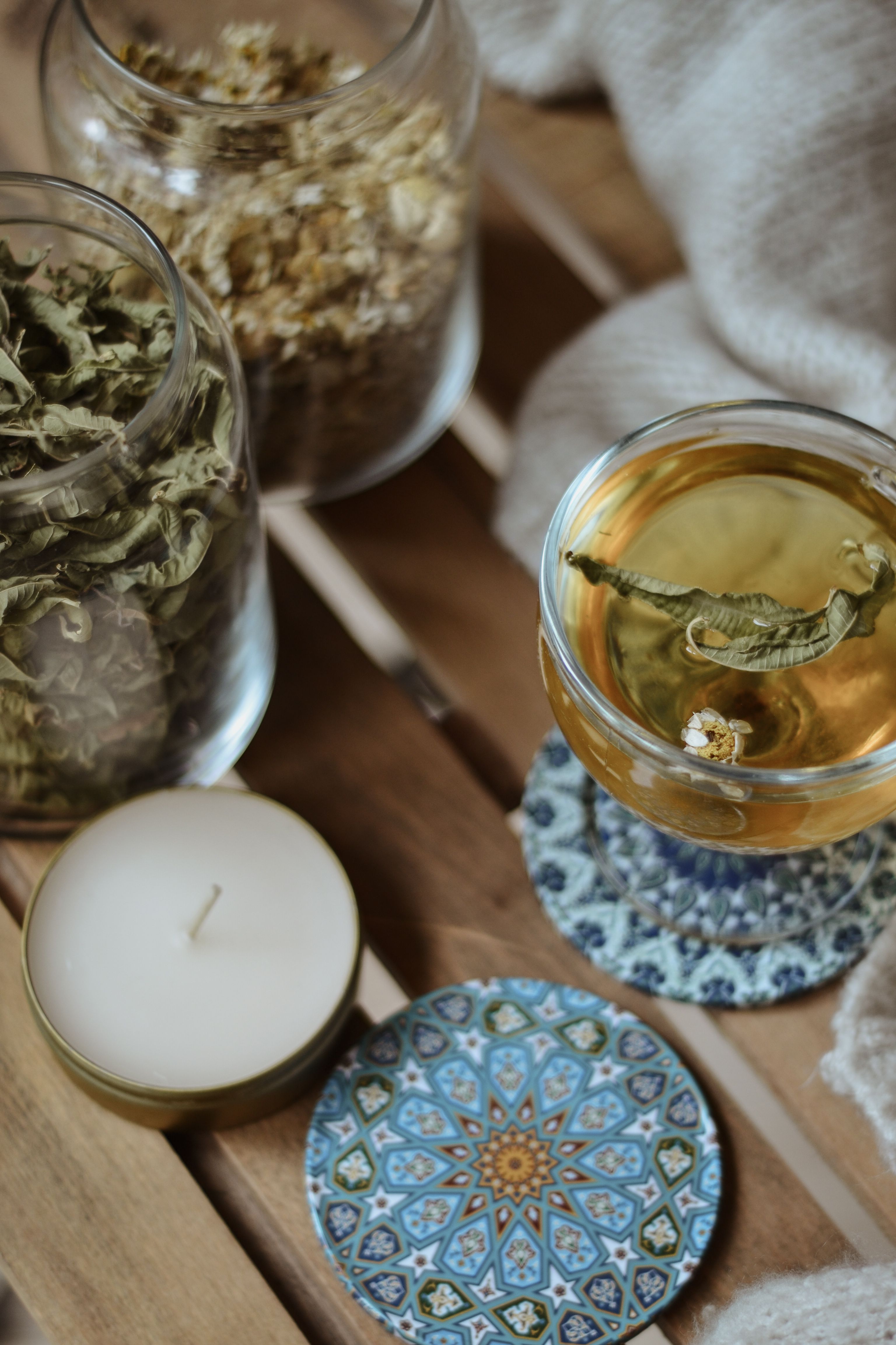 Warm scene featuring herbal tea, dried leaves, and a candle on a rustic wooden table
