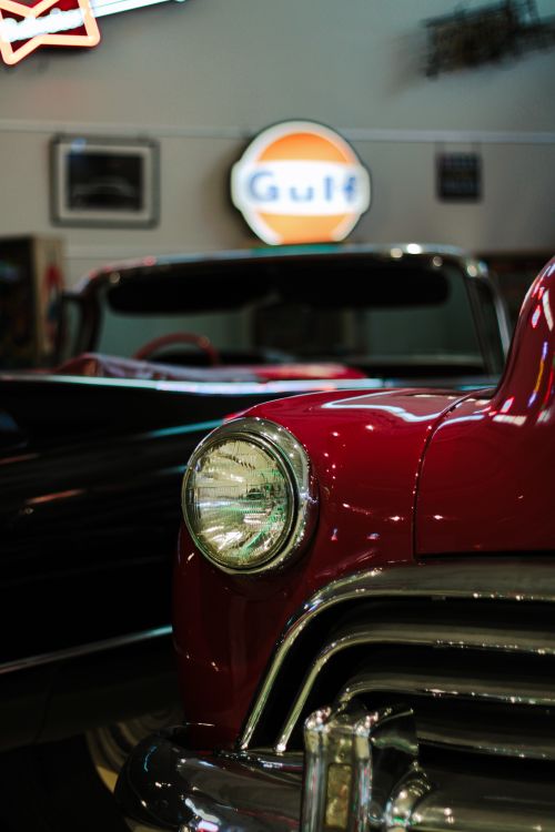Free Close-up of a classic red vintage car's headlight indoors with retro Gulf sign. Stock Photo