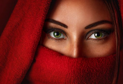 Captivating portrait of a woman with striking green eyes wrapped in a red scarf.