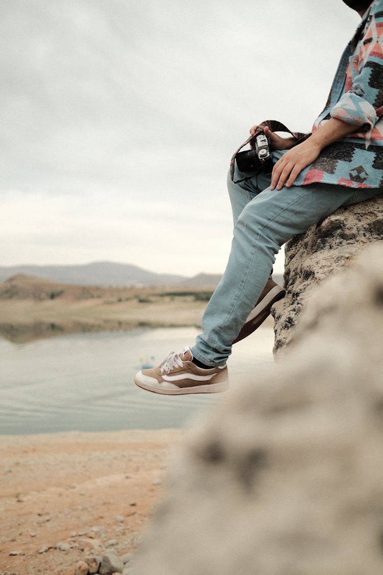 A Photographer Sitting On The Edge Of A Rock