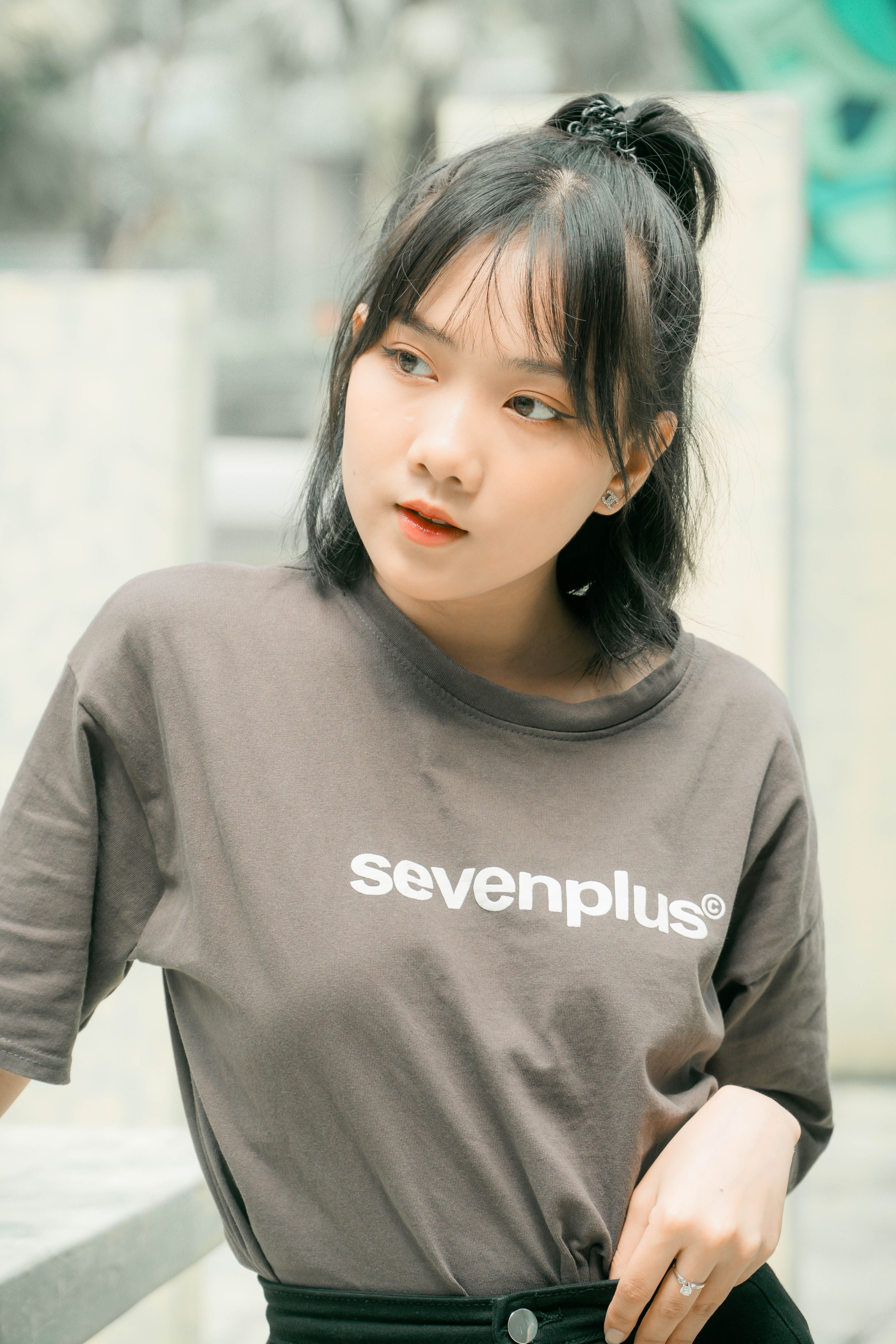 Asian woman in casual fashion poses outdoors wearing a sevenplus t-shirt.