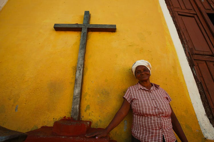 A Woman Standing Beside A Crucifix