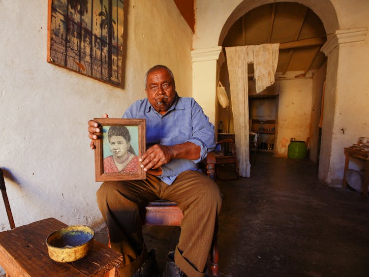 Old Man Sitting In Chair Holding Wife Portrait