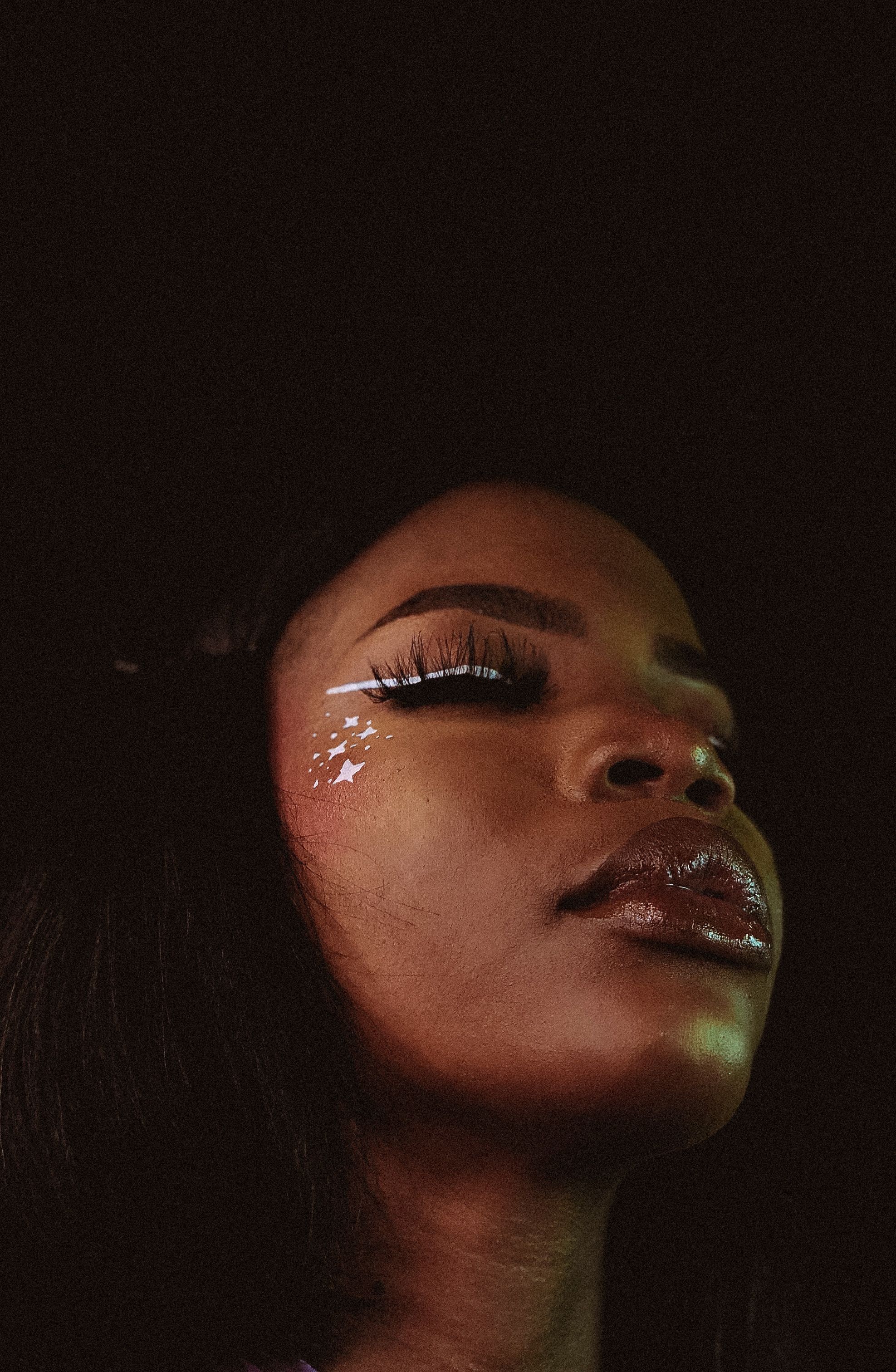 Striking close-up portrait of a woman with elaborate makeup and serene expression.