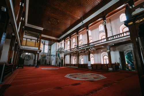 Free Spacious Turkish mosque interior showcasing intricate design, chandeliers, and red carpets. Stock Photo