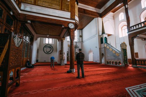 Free Beautiful mosque interior showcasing people in prayer on a vibrant red carpet. Stock Photo