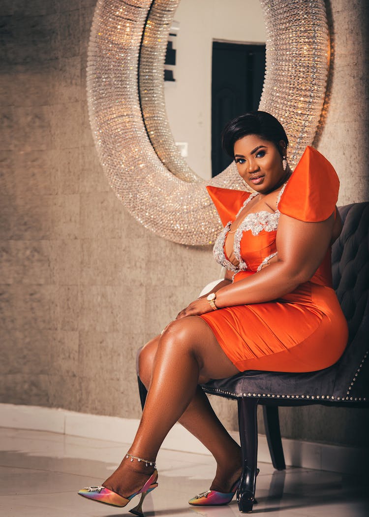 Woman Wearing Orange Silk Dress Sitting By A Crystal Mirror