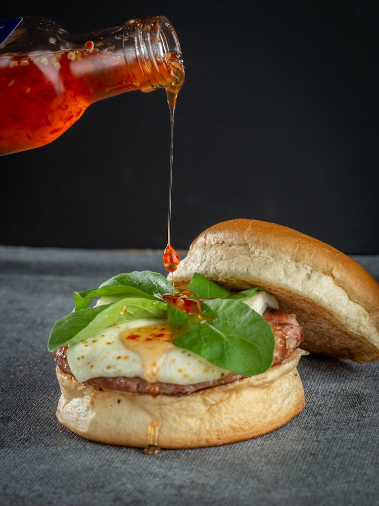 Pouring Sauce At Burger With Fried Egg