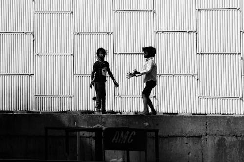 Grayscale Photo of Kids Playing on Concrete Platform