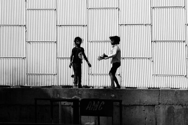 Grayscale Photo Of Kids Playing On Concrete Platform