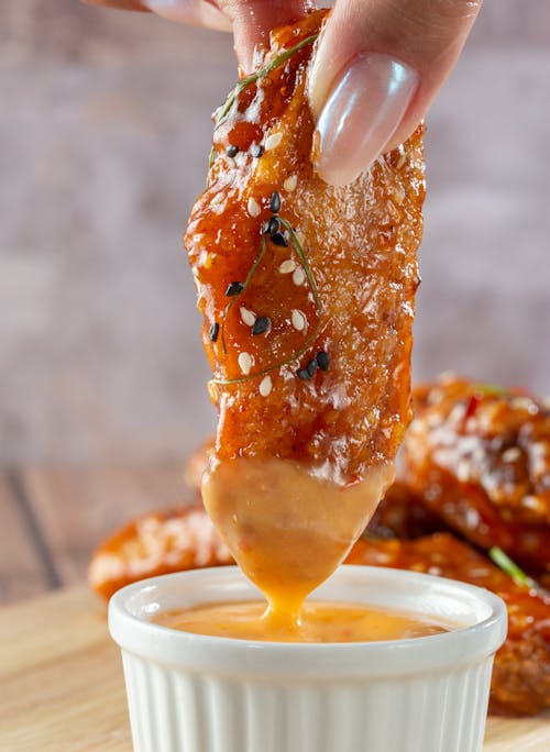 Close-up of Woman Dipping Chicken in Sauce 