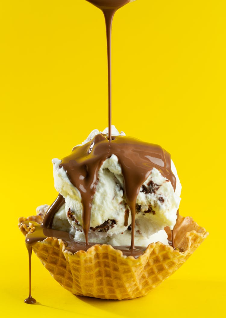 An Ice Cream With Chocolate Syrup On A Waffle Basket