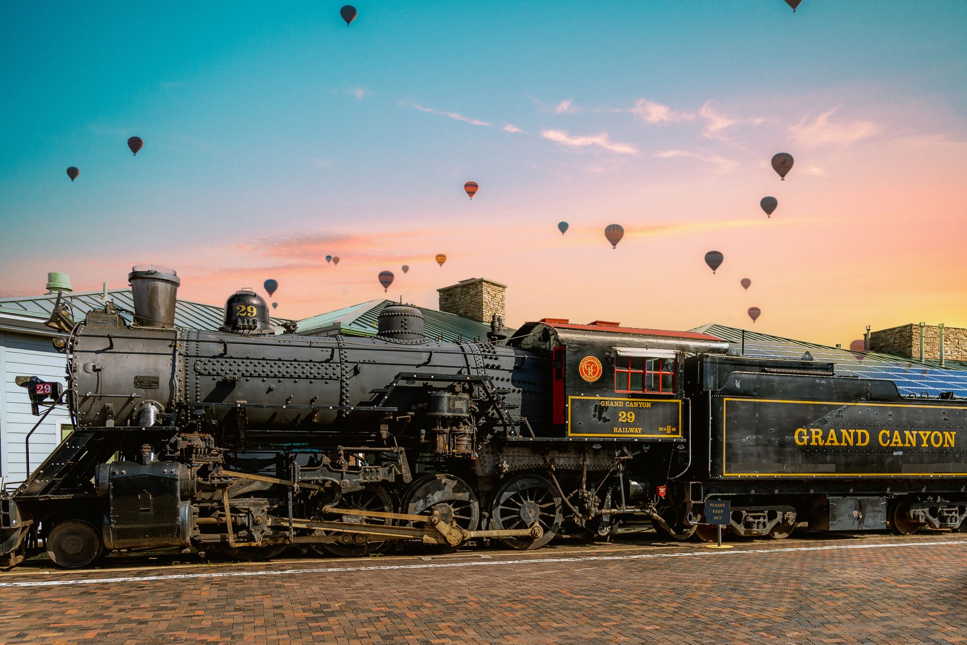 A vintage steam engine at Grand Canyon Village framed by a scenic sunset and hot air balloons.