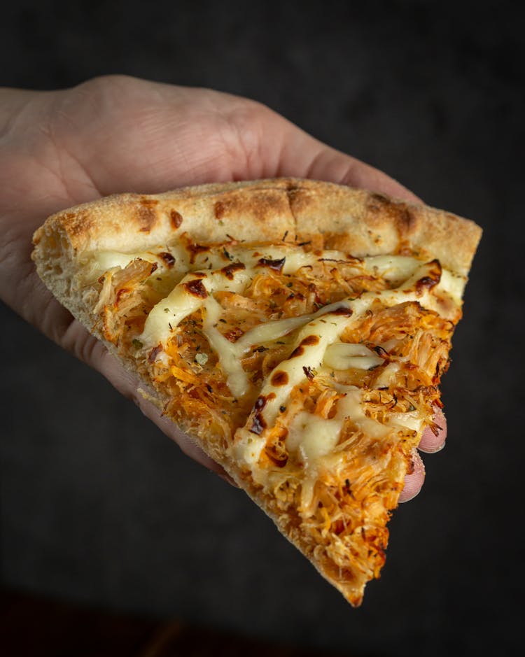 Hand Holding A Slice Of Pizza