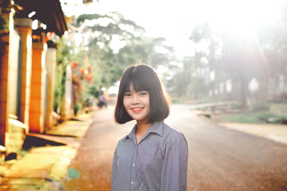 Woman standing on a residential street, photo by Chu Chup Hinh on Pexels