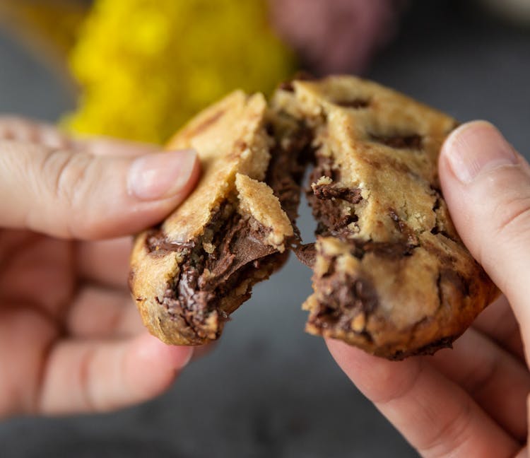 Close-Up Photo Of Person Breaking A Cookie In Half