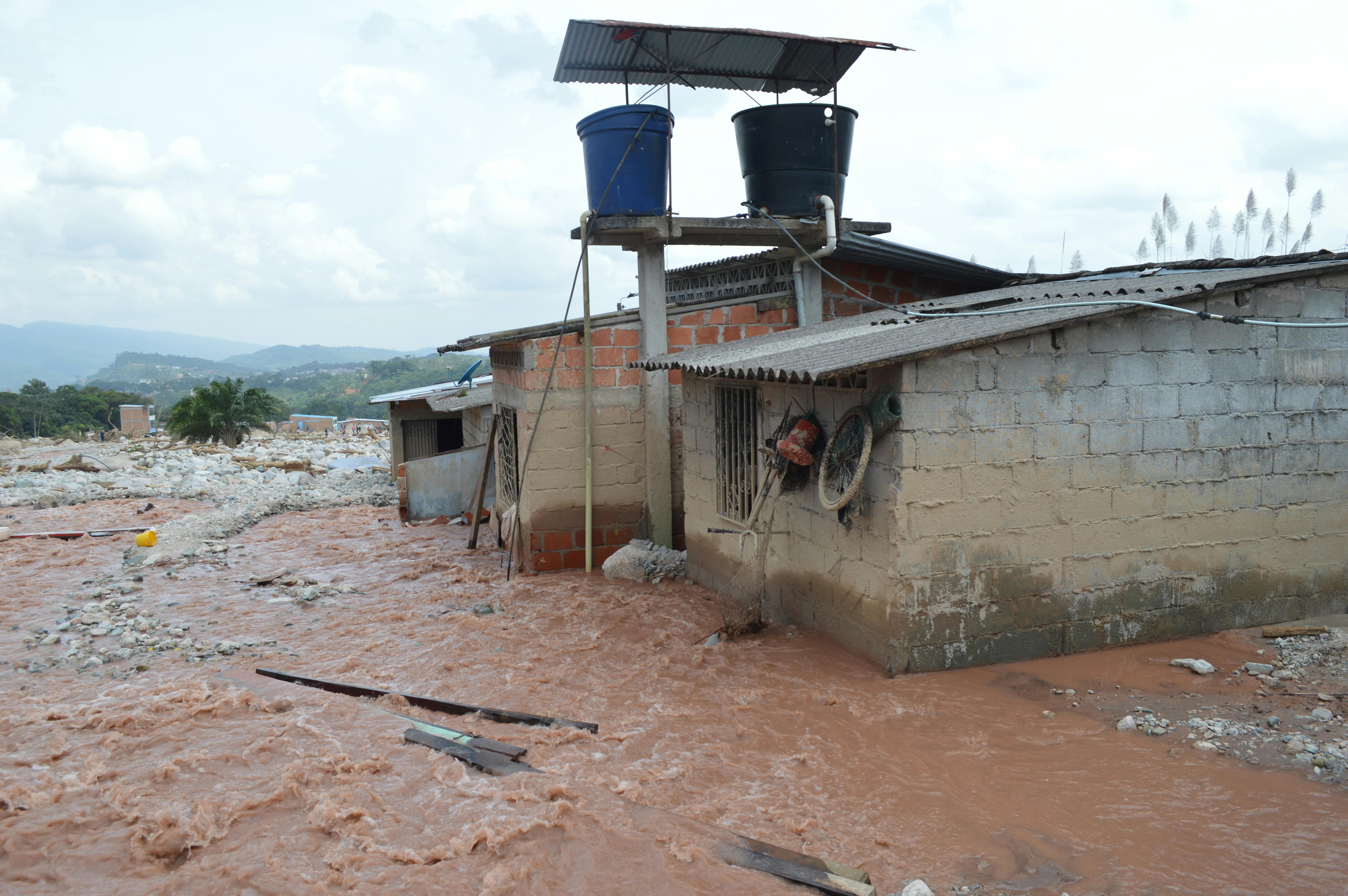 Severe flood damage in Mocoa, Colombia with buildings partially submerged in mudflow.