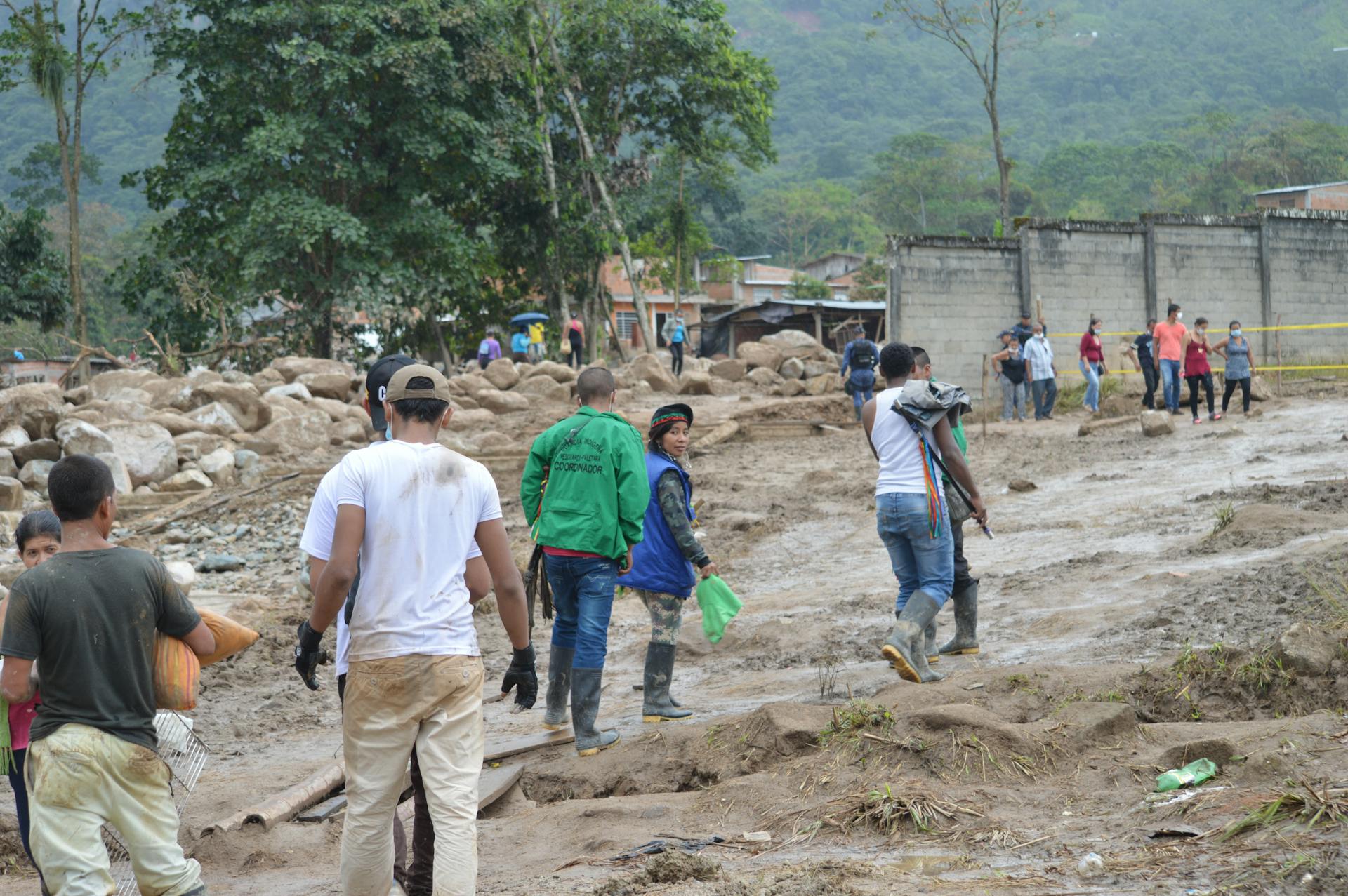 People navigate a muddy terrain in Mocoa, Colombia, post-flood recovery efforts.