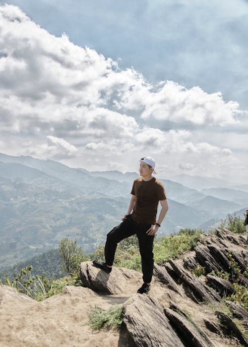 A Man Wearing Cap Standing on the Rock