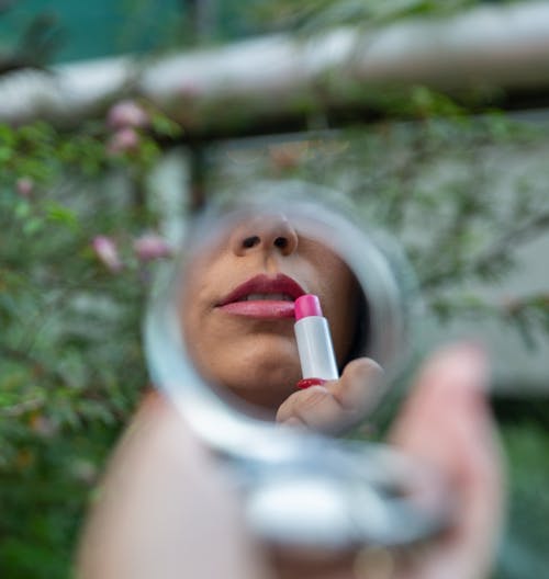 Mirror Reflection of a Woman Putting Lipstick on