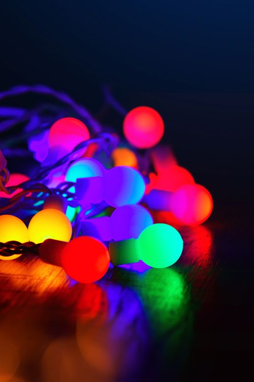 Free A vibrant close-up of colorful string lights glowing in the dark with a bokeh effect. Stock Photo
