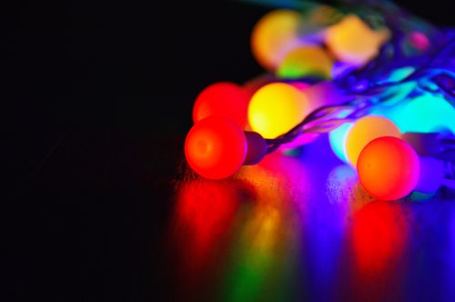 Free Vivid close-up of glowing multicolored Christmas string lights creating a festive mood. Stock Photo