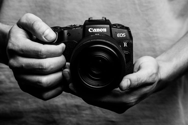 Grayscale Photo Of A Person Holding Black DSLR Camera