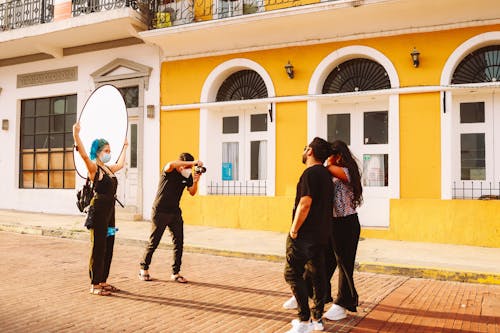 Photographers Taking Photo of a Couple Posing in Casual Wear Standing on Brick Pavement