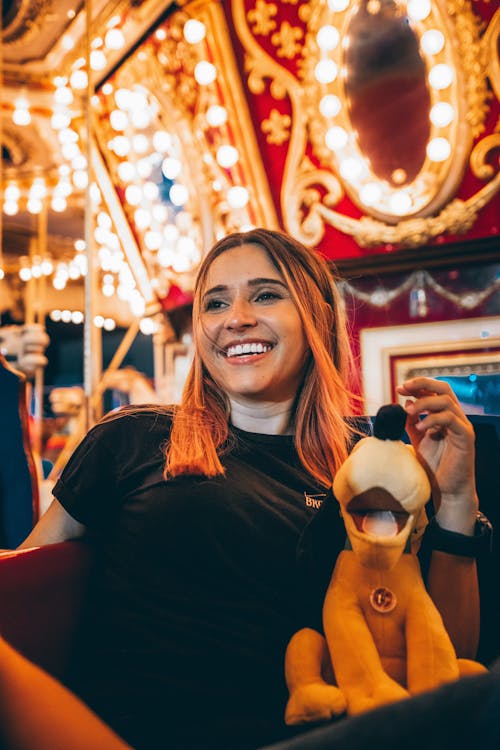 A Woman in Black Crew Neck T-shirt Riding a Carousel 