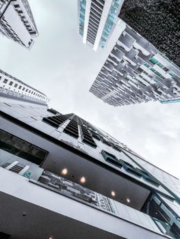 Perspective shot of tall urban buildings with a modern design, viewed from below.