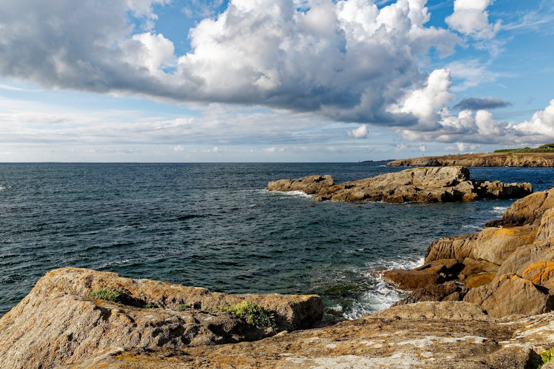 Brown Rock Formation on Sea Under White Clouds and Blue Sky