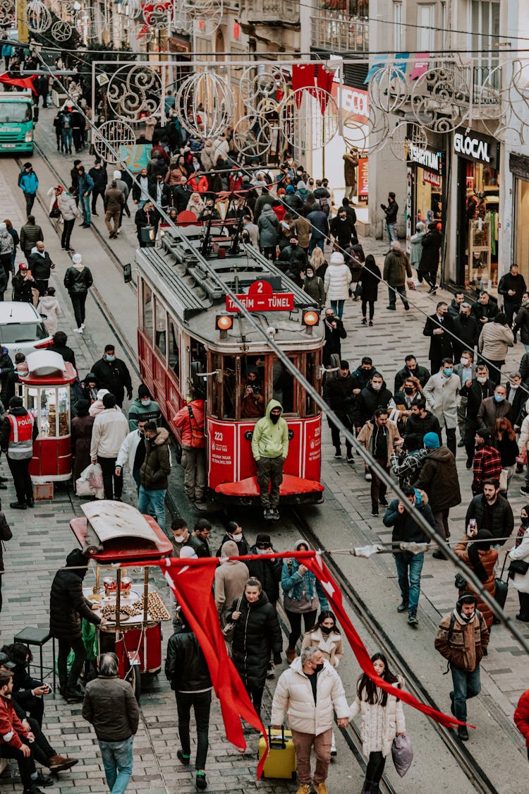 An Aerial Photography Of People Walking On The Street Near The Red Tram