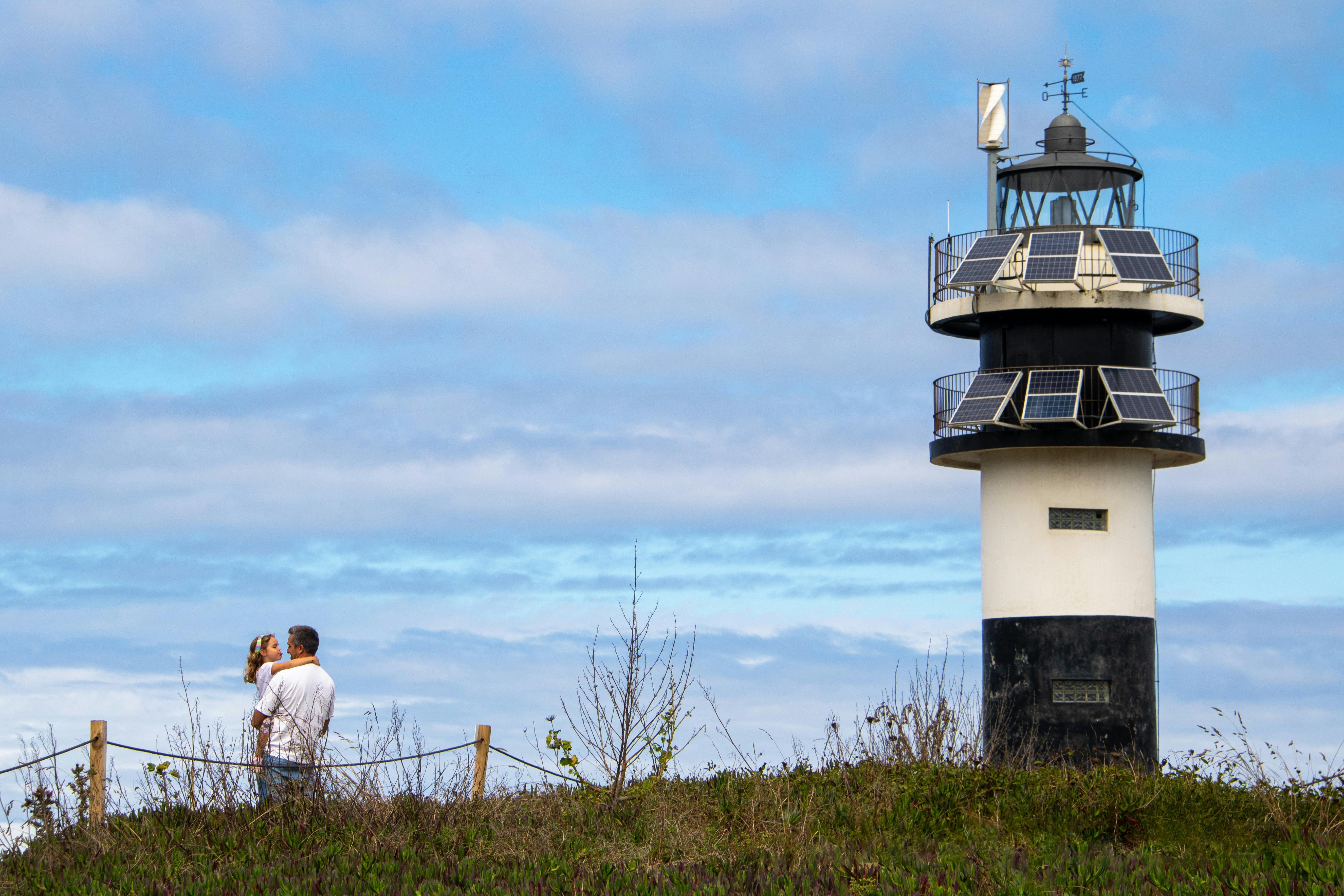 Father Holding His Daughter next to a Lighthouse · Free Stock Photo