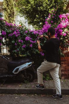 A man photographing vibrant bougainvillea flowers in a street of Istanbul, Turkey.