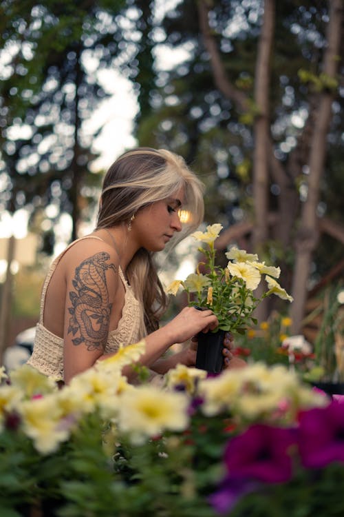 A Side View of a Woman in Knitted Tank Top Holding Flowers