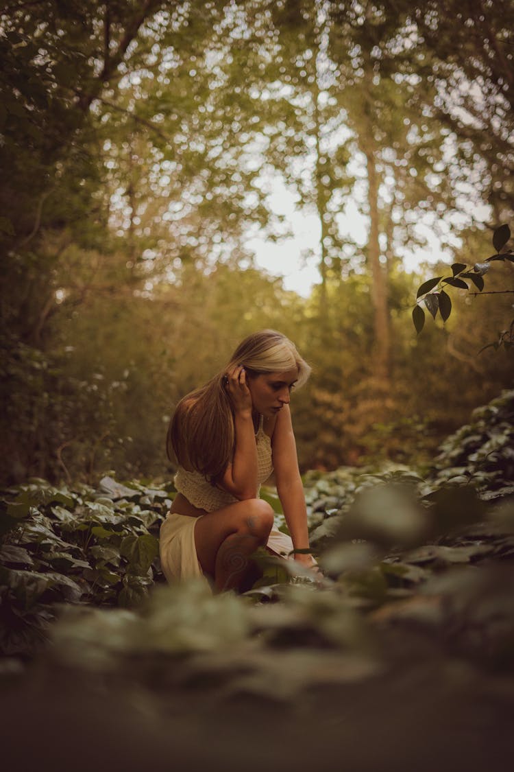 Woman Sitting On Ground In Forest